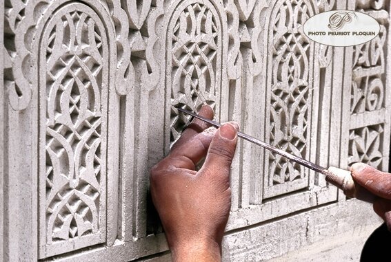 Mains d’un artisan sculptant minutieusement le plâtre